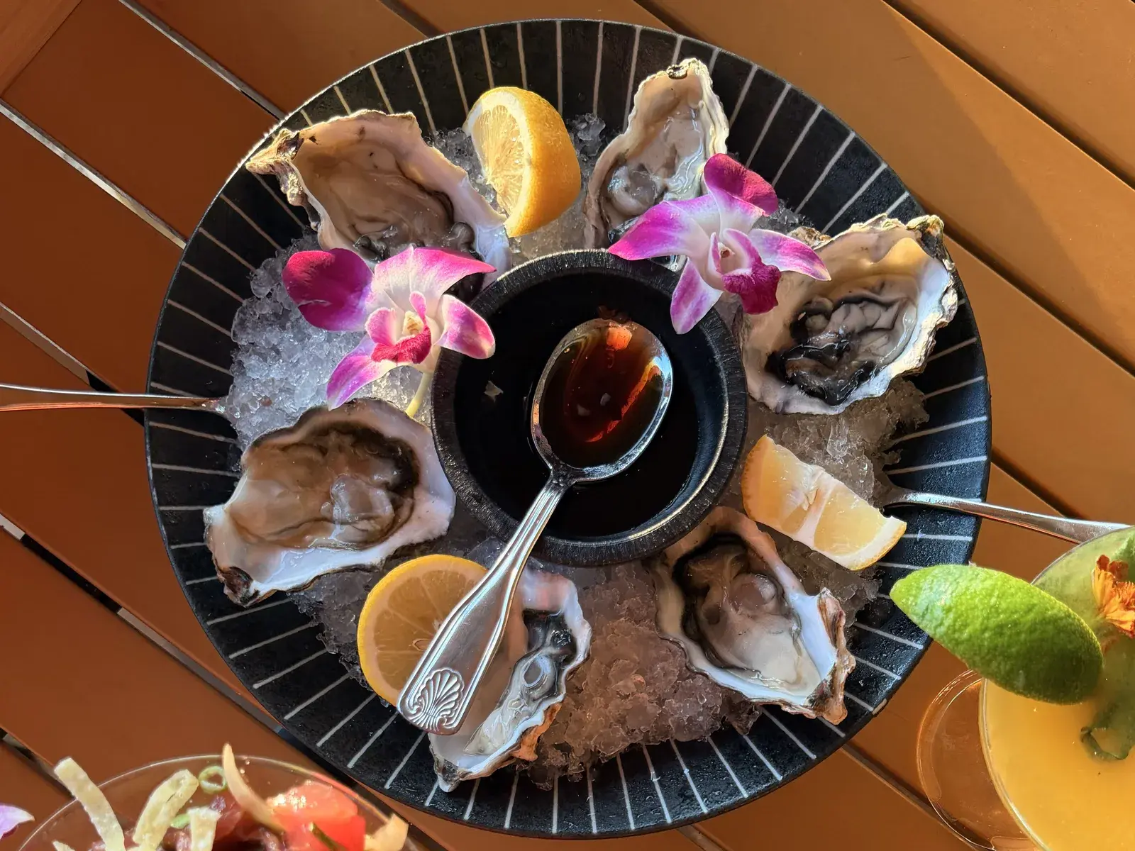Half dozen fresh oysters on the half shell at Voyagers in Kailua-Kona, on crushed ice with lemon, orchids and a bowl of Hawaiian chili-soy sauce