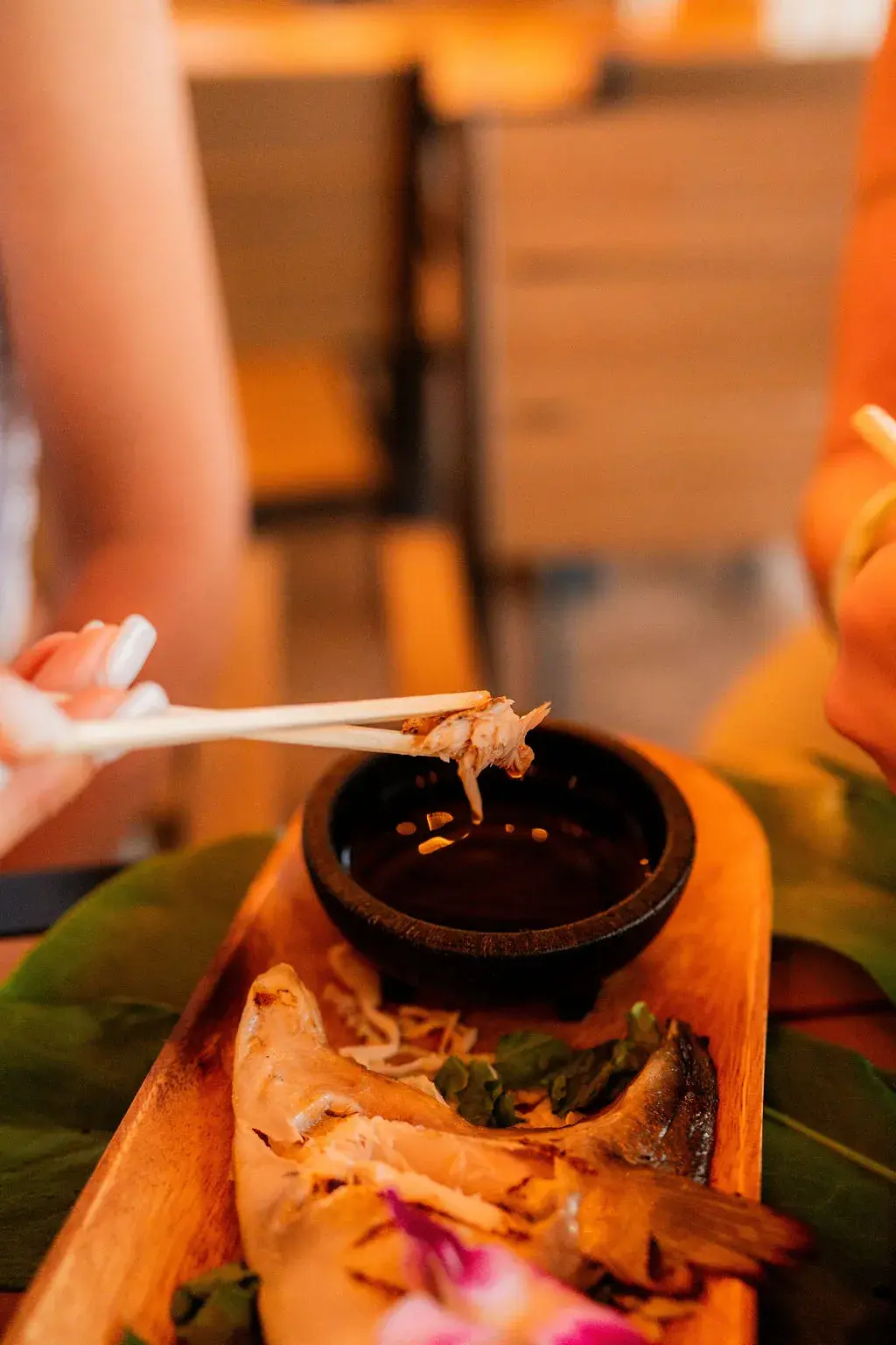 Chopsticks dipping hamachi collar into ginger ponzu at Voyagers