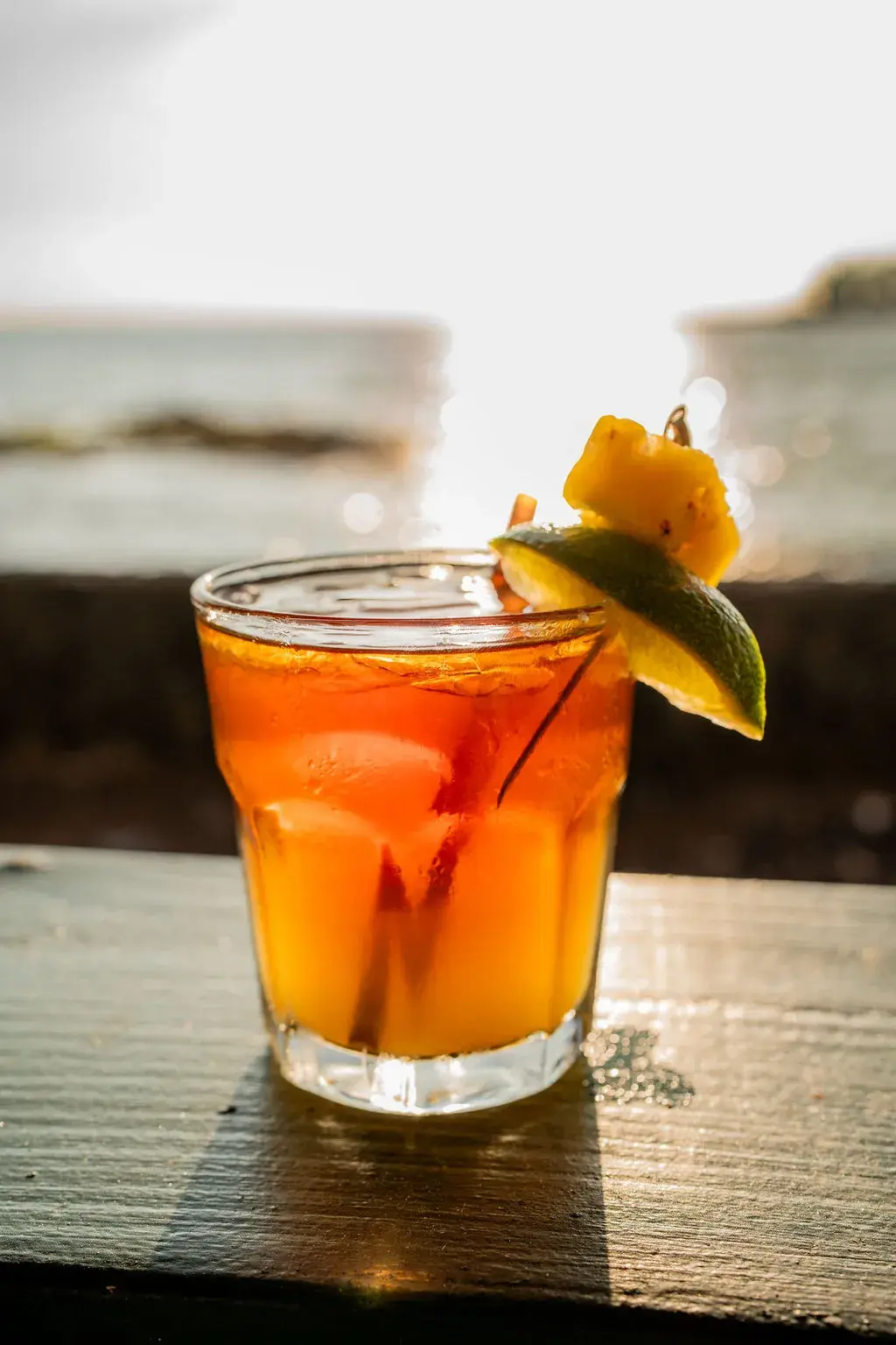 The Sweet Hawaiian Mai Tai on the Voyagers seawall at sunset, its dark rum float over island juices, with pineapple and lime