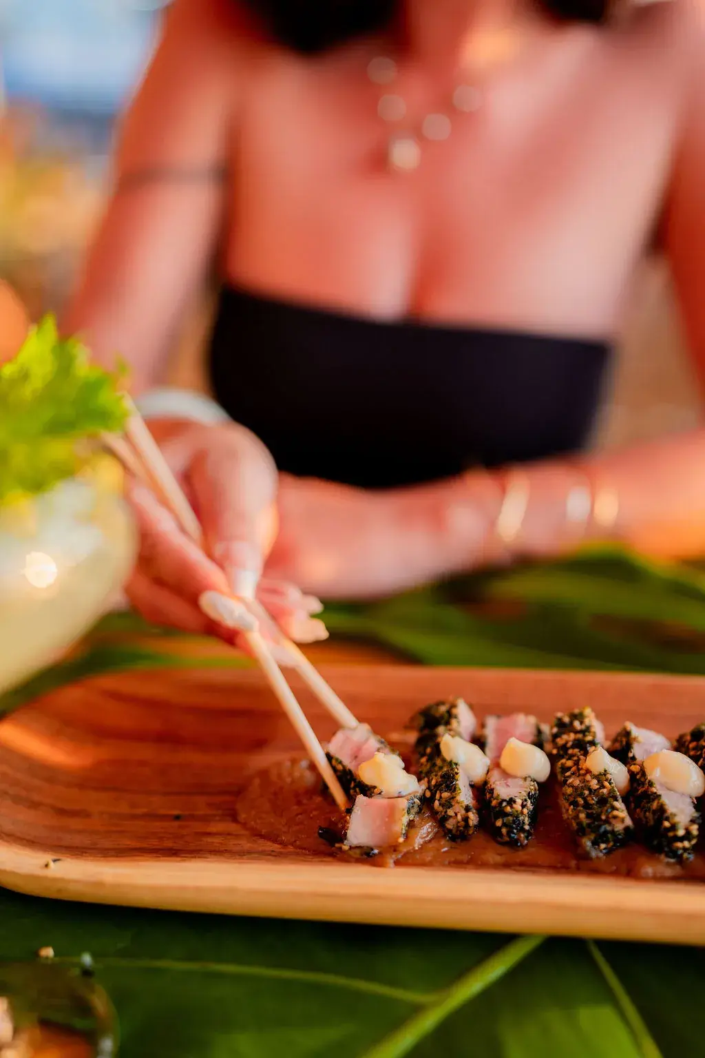Picking up a slice of furikake-crusted seared ahi with chopsticks at Voyagers